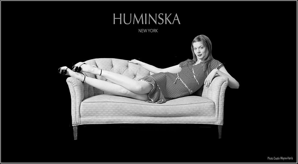 HUMINSKA logo with girl on a couch wearing a red dot dress